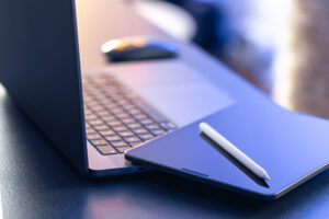 Digital tablet, stylus pen and laptop on the desktop, close up.